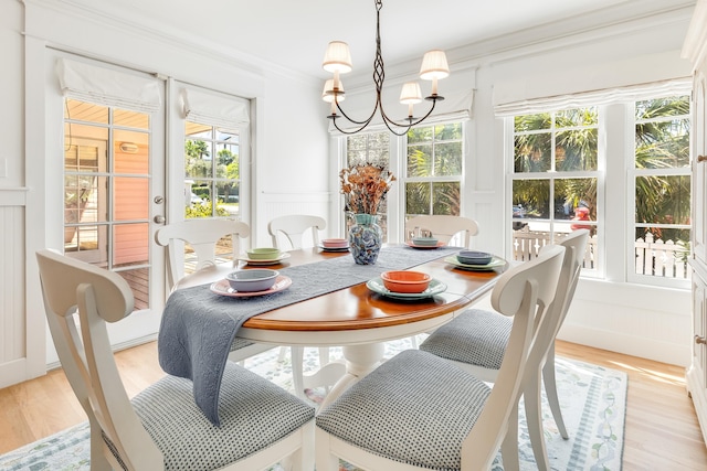 dining area featuring a notable chandelier, plenty of natural light, light wood-style flooring, and ornamental molding