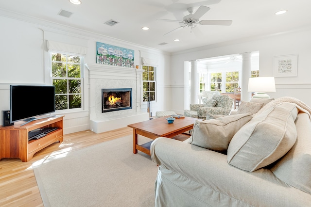 living room featuring a wealth of natural light, visible vents, light wood-style floors, and crown molding