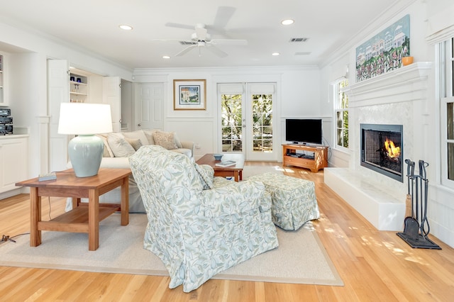 living area with a decorative wall, a fireplace, wood finished floors, and ornamental molding