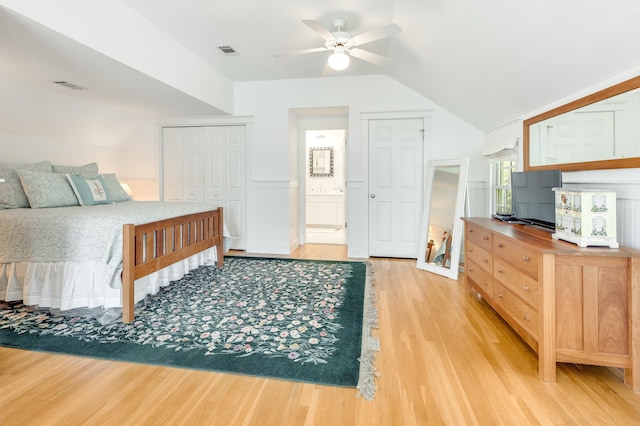 bedroom with light wood-type flooring, visible vents, lofted ceiling, and a closet