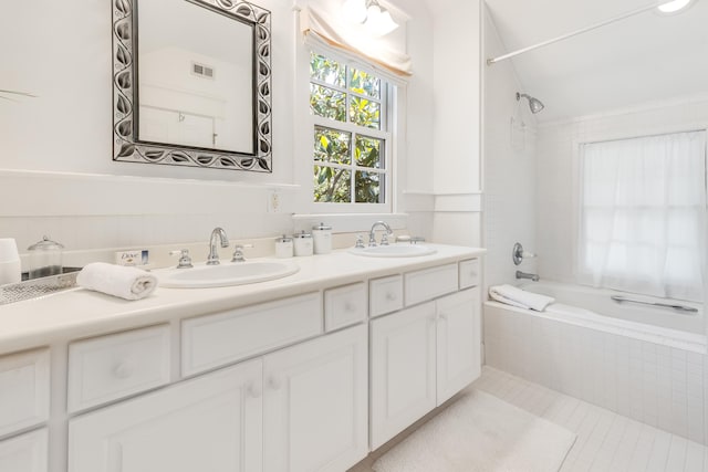 bathroom with a sink, tiled shower / bath, visible vents, and double vanity