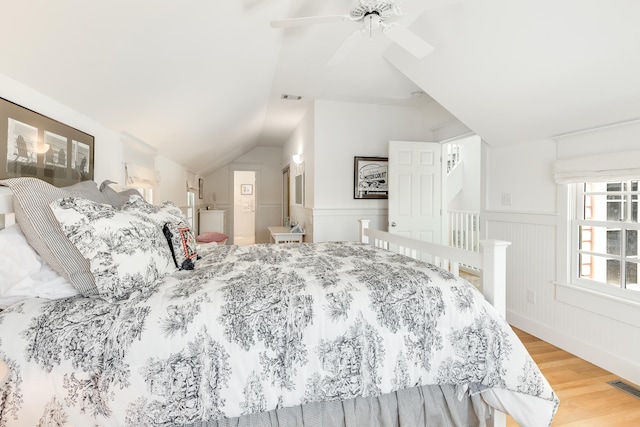 bedroom with visible vents, wood finished floors, wainscoting, and vaulted ceiling