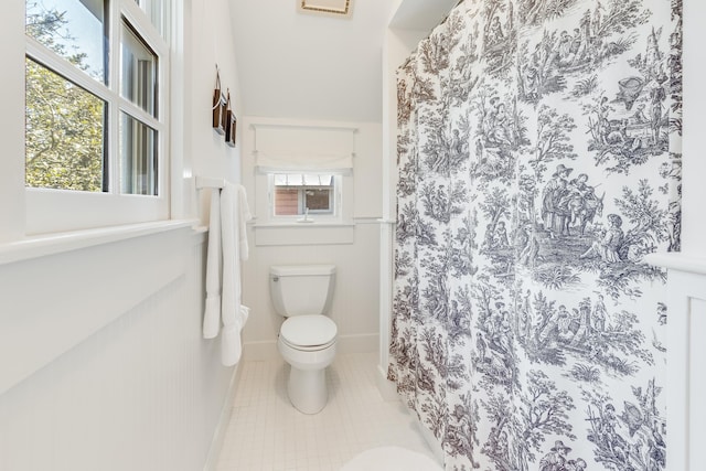 full bathroom featuring tile patterned flooring, a healthy amount of sunlight, toilet, and baseboards