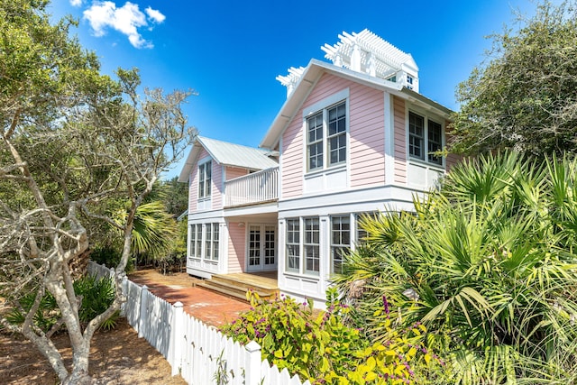 view of home's exterior featuring a balcony, french doors, and fence