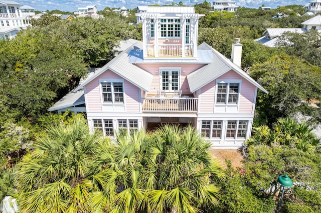 rear view of house featuring a balcony and a chimney