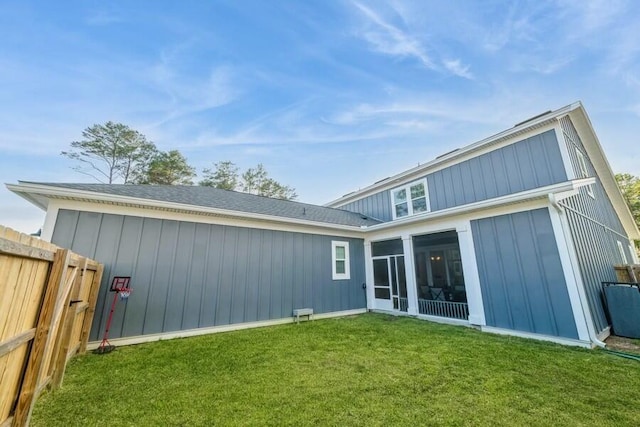 back of house featuring a yard, board and batten siding, fence, and a sunroom