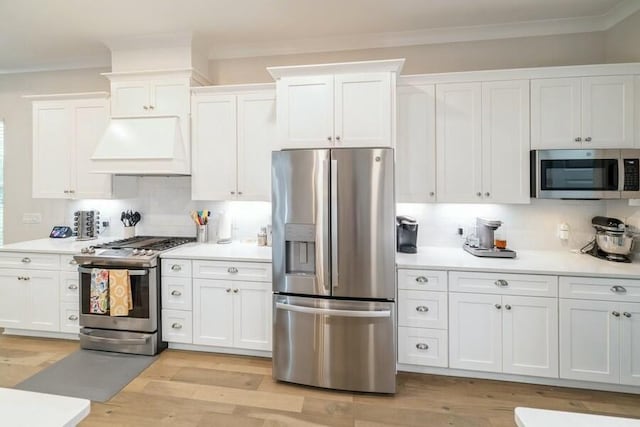 kitchen featuring stainless steel appliances, light countertops, white cabinets, and premium range hood