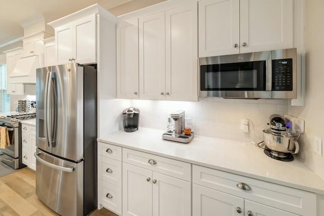 kitchen featuring light wood finished floors, light countertops, decorative backsplash, appliances with stainless steel finishes, and white cabinetry