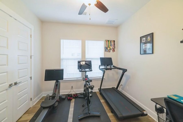 workout room with light wood-style flooring, visible vents, baseboards, and ceiling fan