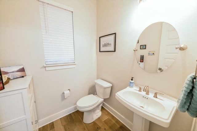 bathroom featuring a sink, toilet, baseboards, and wood finished floors