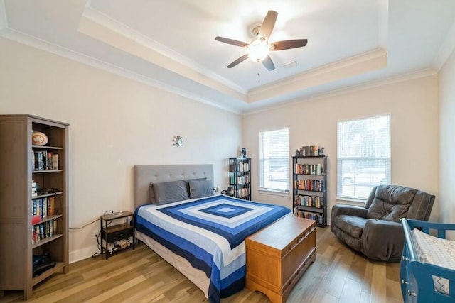 bedroom featuring light wood finished floors, a tray ceiling, and crown molding