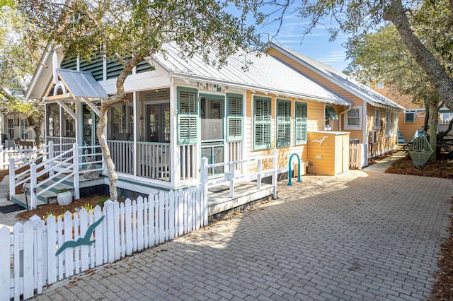 view of front of home with a fenced front yard, a sunroom, and metal roof