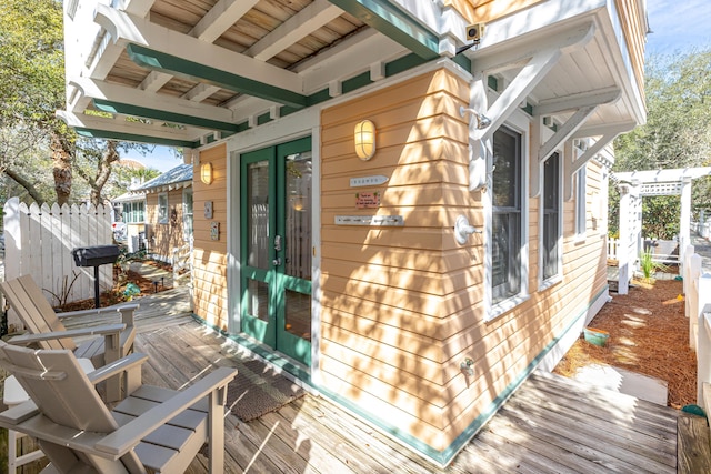 exterior space with fence, a deck, and french doors