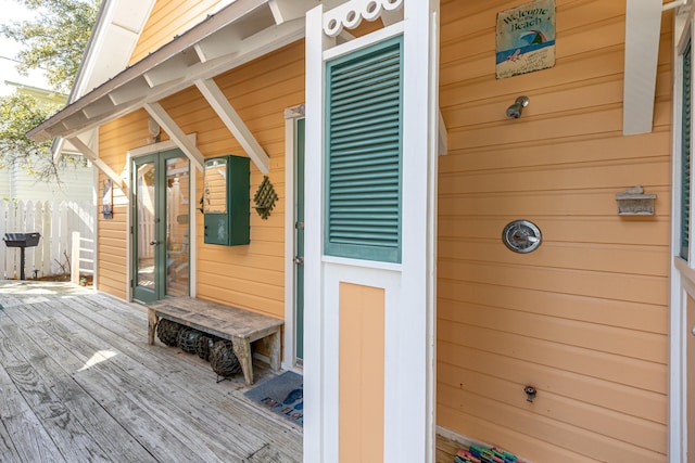 property entrance featuring fence, a deck, and french doors