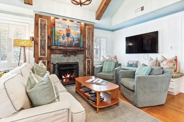 living area with a lit fireplace, a wealth of natural light, wood finished floors, and visible vents