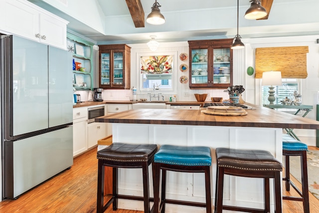 kitchen featuring stainless steel appliances, butcher block countertops, light wood-type flooring, beam ceiling, and glass insert cabinets