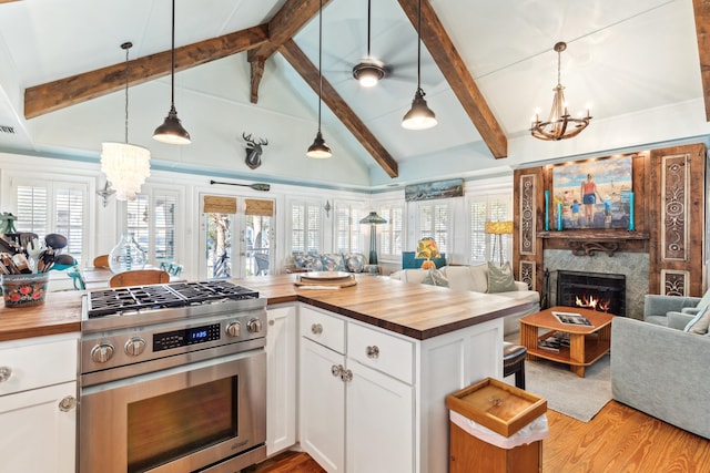 kitchen featuring butcher block countertops, stainless steel range with gas cooktop, open floor plan, and a notable chandelier