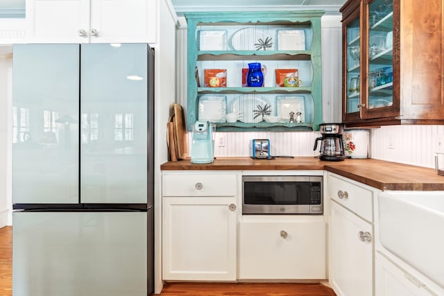 kitchen with white cabinets, butcher block countertops, glass insert cabinets, wood finished floors, and stainless steel appliances