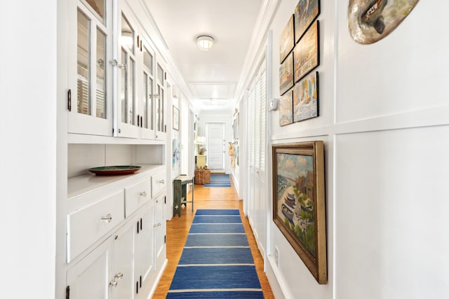 hallway with ornamental molding and light wood finished floors