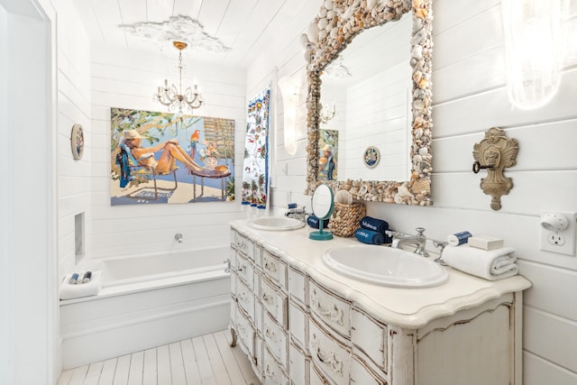 full bath with double vanity, an inviting chandelier, a washtub, and a sink