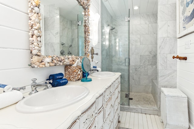 full bathroom with a sink, double vanity, and a shower stall