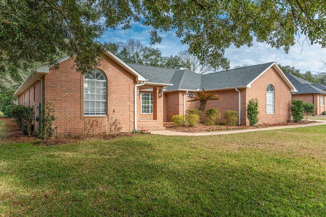 ranch-style home with brick siding, a front yard, and a shingled roof