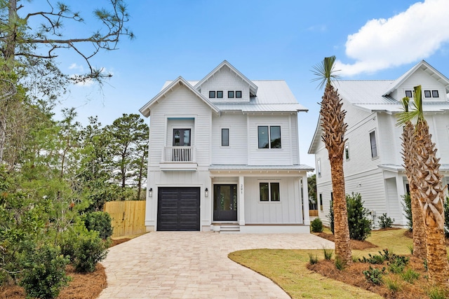 modern inspired farmhouse with decorative driveway, an attached garage, board and batten siding, a standing seam roof, and metal roof