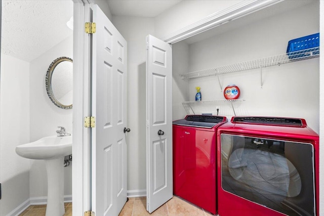 washroom featuring light tile patterned floors, laundry area, separate washer and dryer, and baseboards