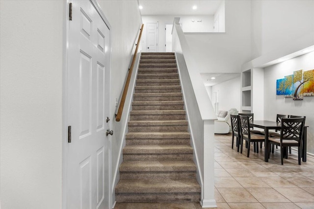 stairs featuring a towering ceiling, tile patterned flooring, baseboards, and recessed lighting