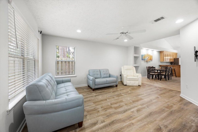 living area with a textured ceiling, light wood-style flooring, visible vents, and recessed lighting