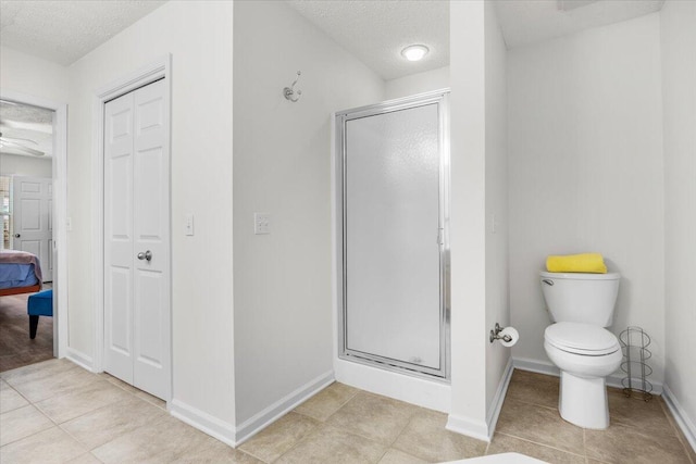 full bath with a textured ceiling, a closet, toilet, and a stall shower