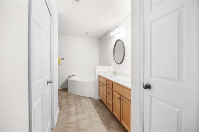 bathroom with double vanity, a sink, a textured ceiling, baseboards, and a bath