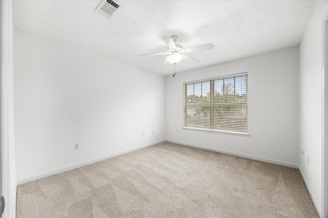 unfurnished room with light carpet, a textured ceiling, visible vents, and a ceiling fan