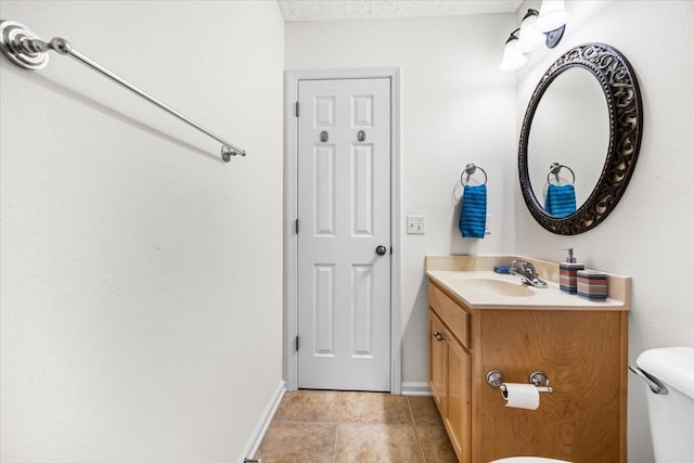 bathroom with baseboards, toilet, tile patterned floors, a textured ceiling, and vanity