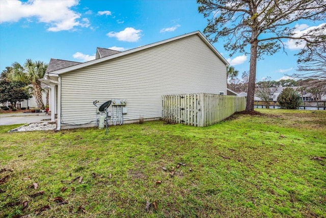 view of side of home with fence and a yard