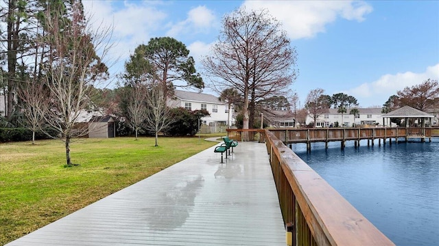 view of dock with a water view, a residential view, and a yard