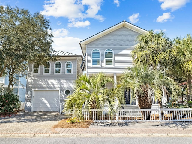 view of front of home featuring fence, covered porch, metal roof, decorative driveway, and a standing seam roof