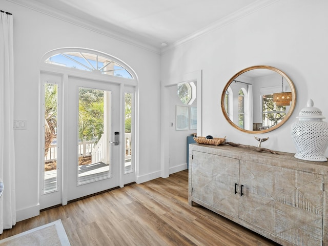 foyer featuring baseboards, plenty of natural light, wood finished floors, and crown molding