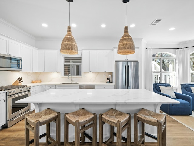 kitchen featuring visible vents, appliances with stainless steel finishes, a sink, and ornamental molding