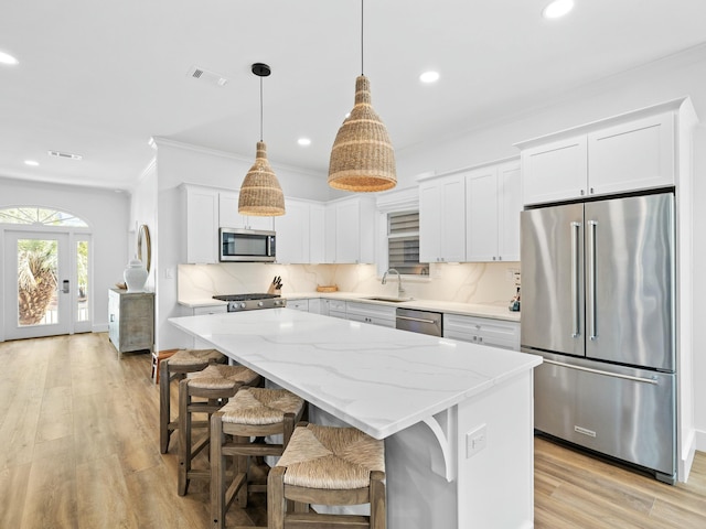 kitchen with visible vents, a kitchen island, a sink, stainless steel appliances, and backsplash