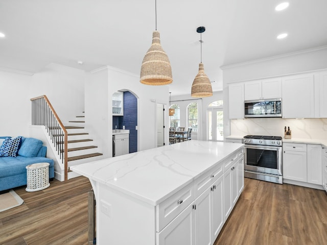 kitchen with appliances with stainless steel finishes, dark wood-style flooring, crown molding, and a kitchen island