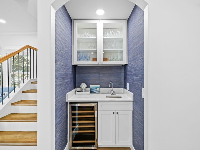 bar with arched walkways, wine cooler, a sink, indoor wet bar, and wallpapered walls