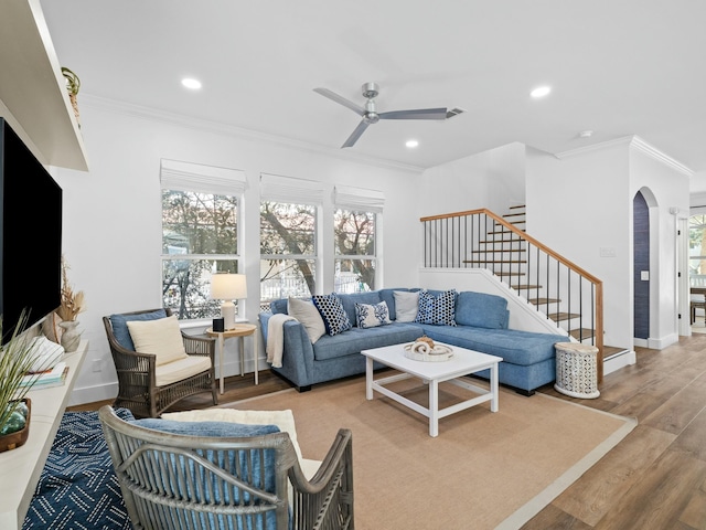 living room with a healthy amount of sunlight, arched walkways, wood finished floors, and ornamental molding