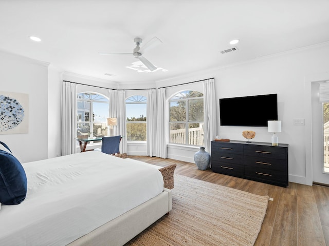 bedroom featuring light wood-style flooring, multiple windows, visible vents, and crown molding