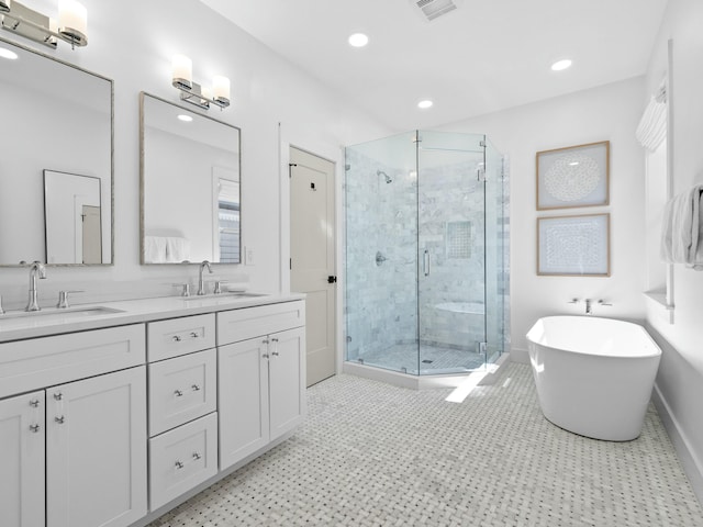 full bath with double vanity, a freestanding tub, a stall shower, and a sink