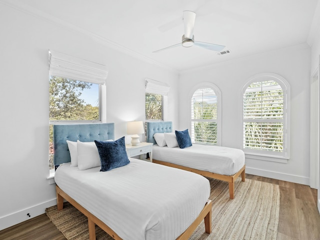 bedroom featuring baseboards, visible vents, ceiling fan, wood finished floors, and crown molding