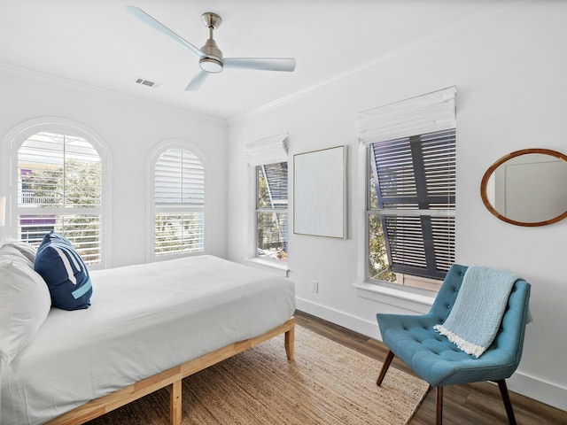 bedroom with visible vents, crown molding, and wood finished floors