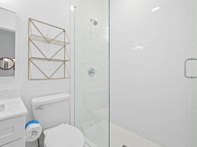 bathroom featuring toilet, tiled shower, and vanity