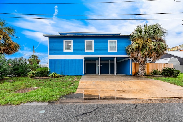 view of front of house with driveway, a carport, and a front yard