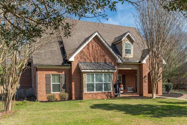 view of front of home with roof with shingles, a front yard, and brick siding